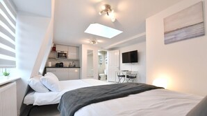Una camera da letto moderna con un letto, una scrivania, una TV a schermo piatto e un velux.