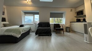 Una camera da letto moderna con un lucernario, un letto, una sedia e un angolo cottura.