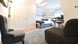 Un dormitorio con cama, una silla, un escritorio y una lámpara.