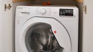 Una lavadora blanca con panel de control y una pegatina roja en la puerta.
