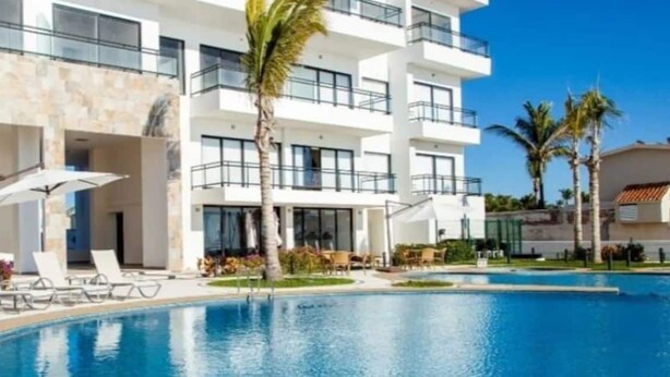 A modern hotel with a swimming pool, sun loungers, and palm trees. - Condos Perla (Mazatlán)