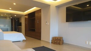 A modern hotel room with a large bed, a flat-screen TV mounted on the wall, and a walk-in closet. - Condos Perla (Mazatlán)