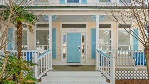 A two-story house with a blue door, white railings, and a small porch. - Sleeps 16 / Walk to Beach / 6BR w/ Bunk Room / Perfect for Families & Groups (Destin)