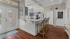 A modern kitchen with a central island, white cabinetry, and a hanging light fixture. - Sleeps 16 / Walk to Beach / 6BR w/ Bunk Room / Perfect for Families & Groups (Destin)