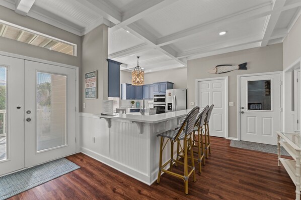 A modern kitchen with a central island, white cabinetry, and a hanging light fixture.