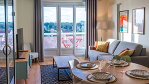 Una sala de estar moderna con comedor, ventanas grandes y vistas a la ciudad.
