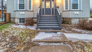A two-story house with a front entrance, a porch, and a staircase leading to the door. - Riverside Inn (New Glasgow)