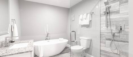 A modern bathroom with a freestanding bathtub, a glass-enclosed shower, and a toilet.