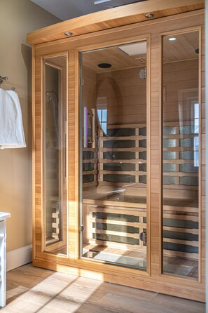 A wooden sauna with glass doors, a wooden bench, and a towel rack.