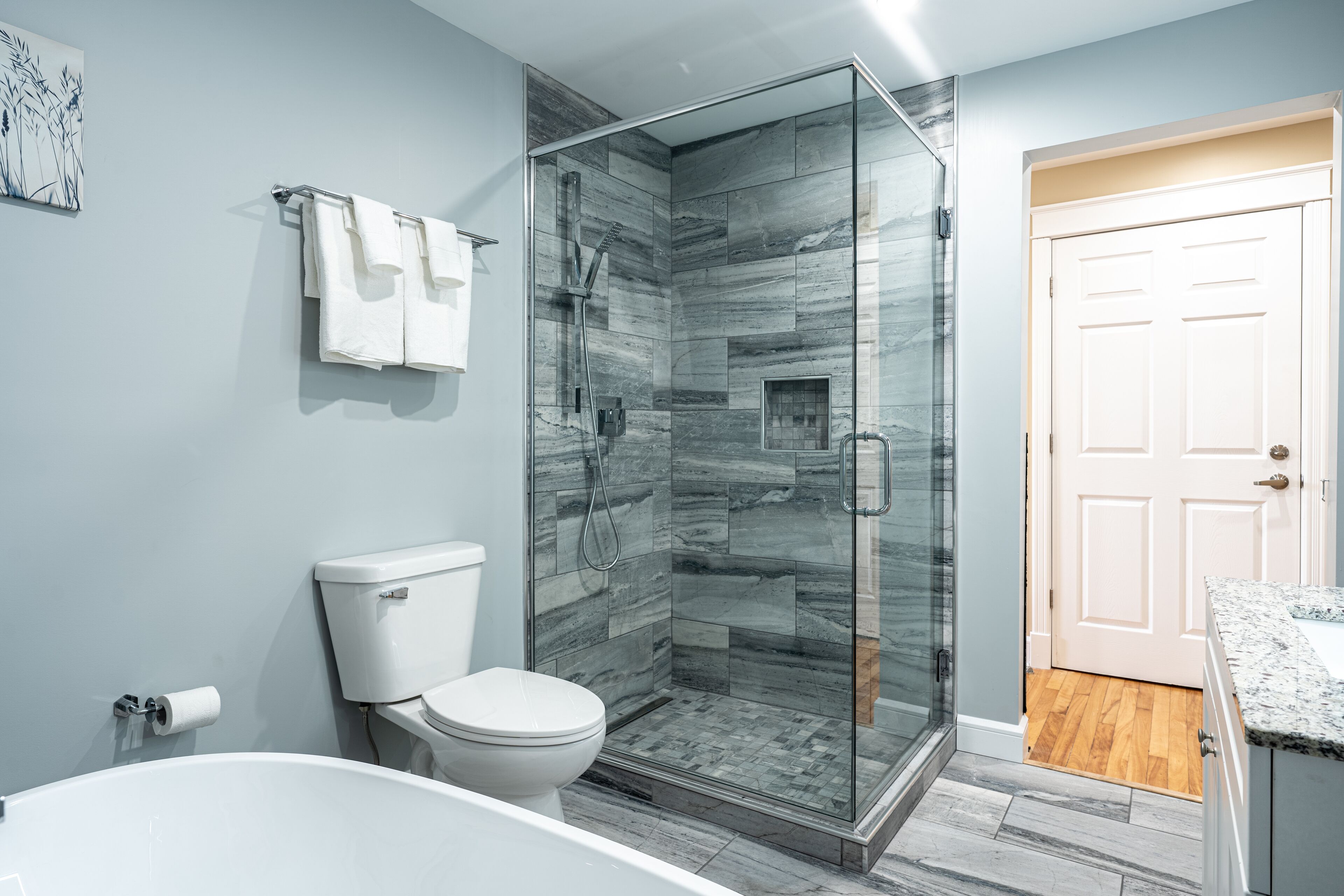A modern bathroom with a glass-enclosed shower, a toilet, and a bathtub.