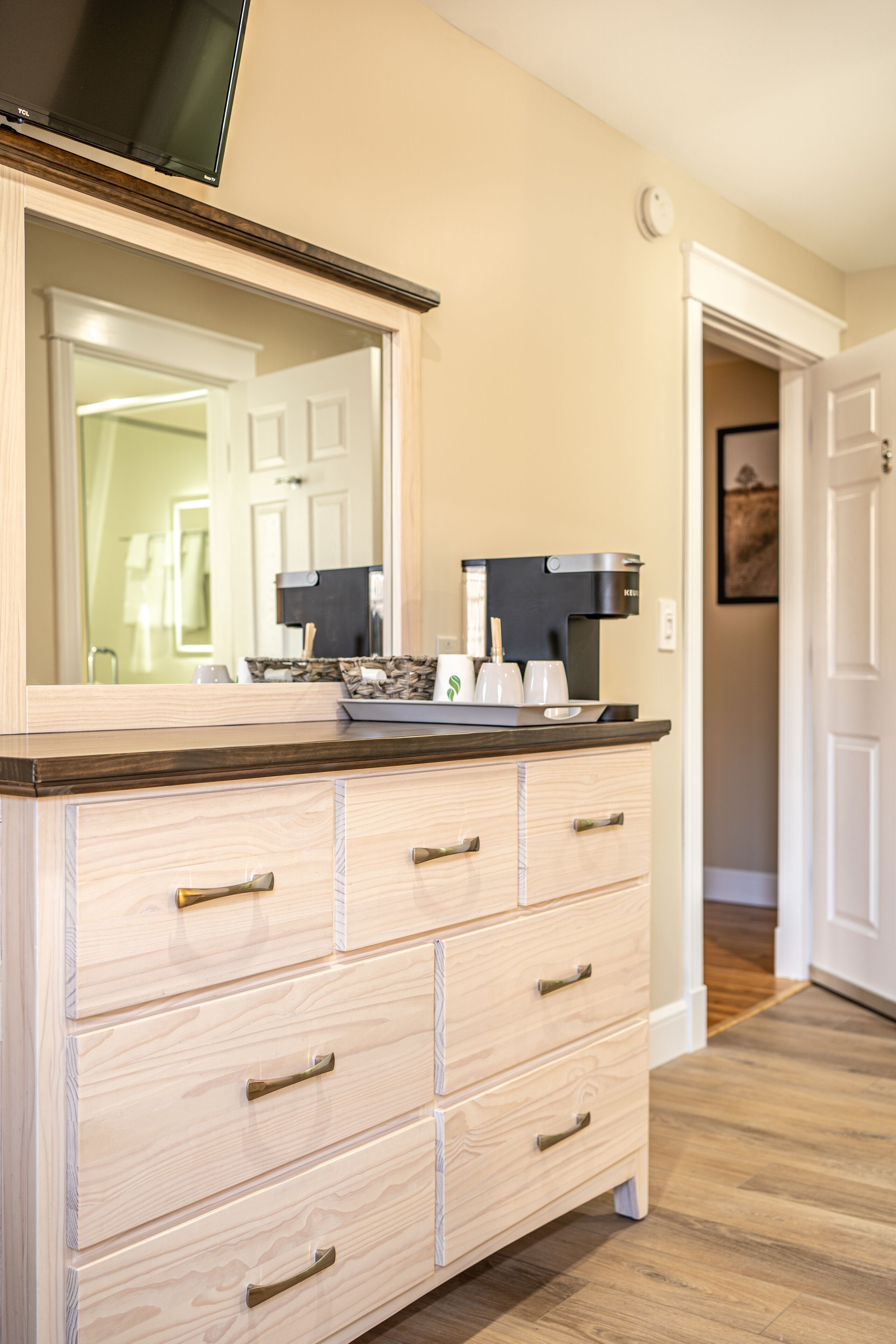 A wooden dresser with drawers and a mirror above it.