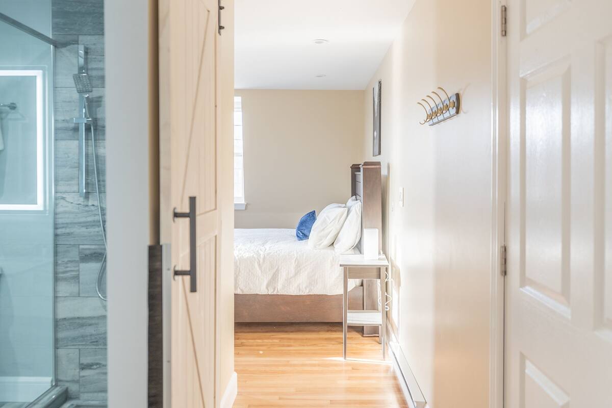 Un pasillo que conduce a un dormitorio con cama, mesita de noche y armario.