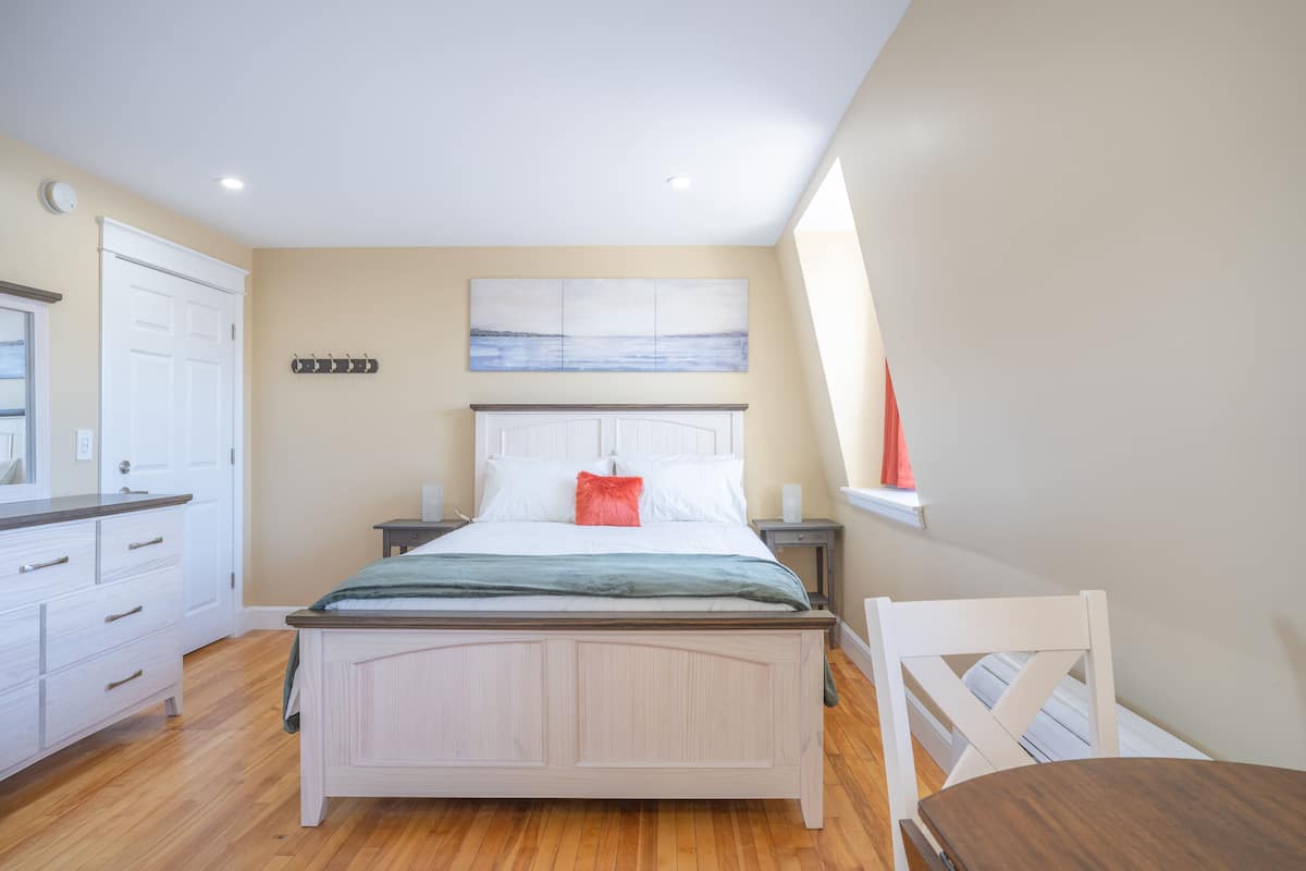 Un dormitorio con cama, mesita de noche, cómoda y ventana.