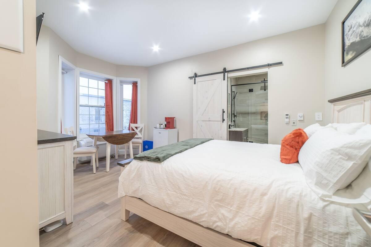Un dormitorio con cama, escritorio, silla, puerta corrediza y ventana.