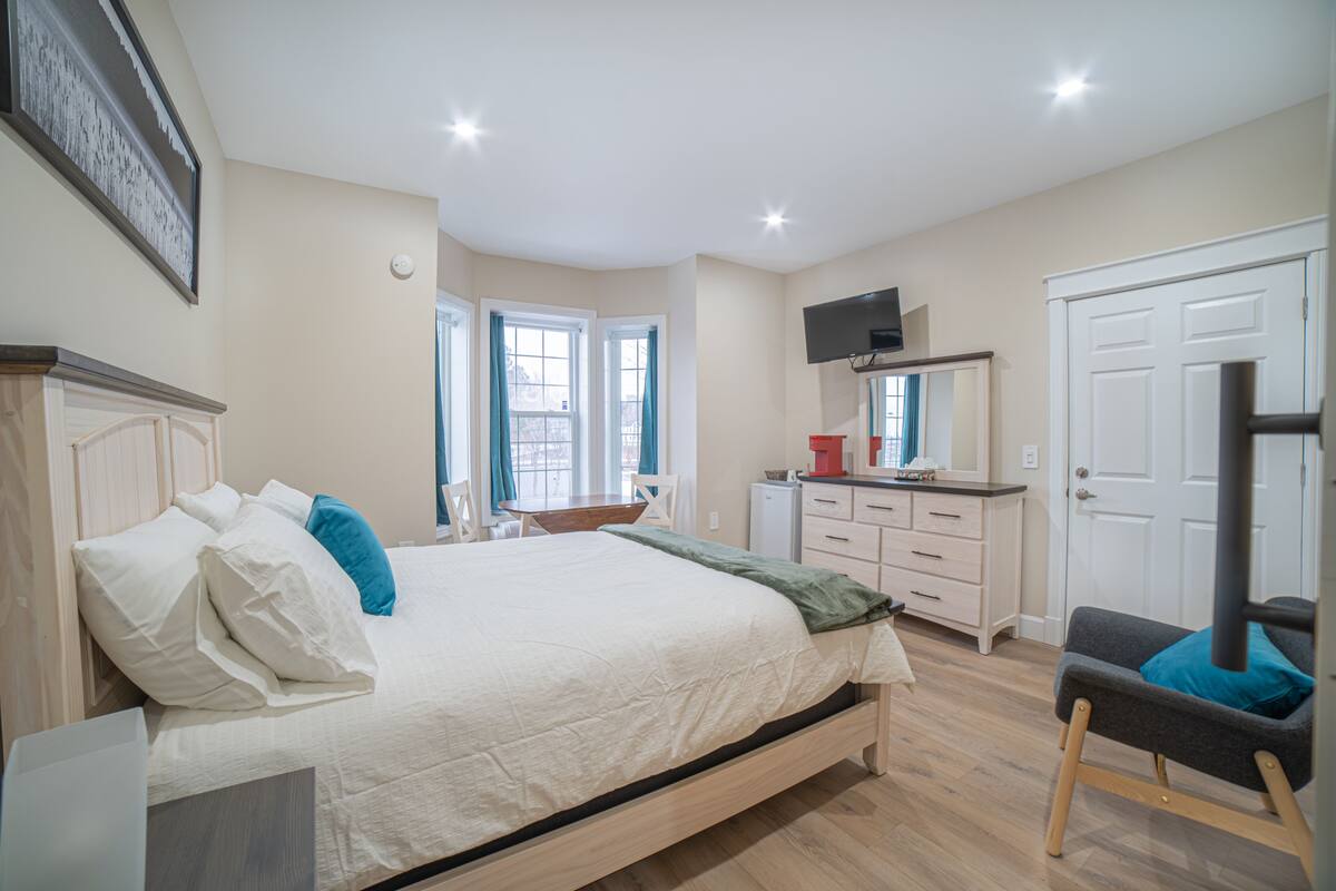 Un dormitorio con cama, escritorio, silla, televisor y armario.