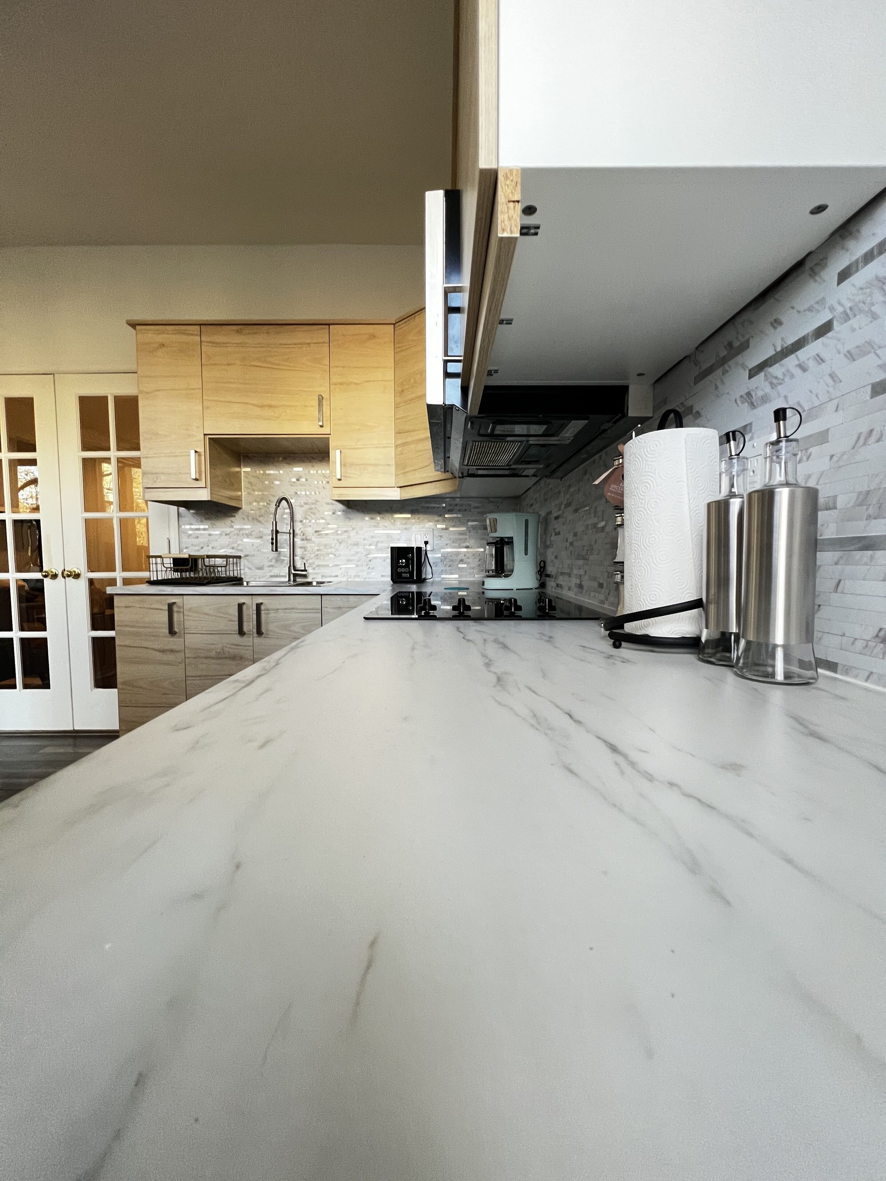 Una cocina moderna con armarios de madera, encimera de mármol y electrodomésticos de acero inoxidable.