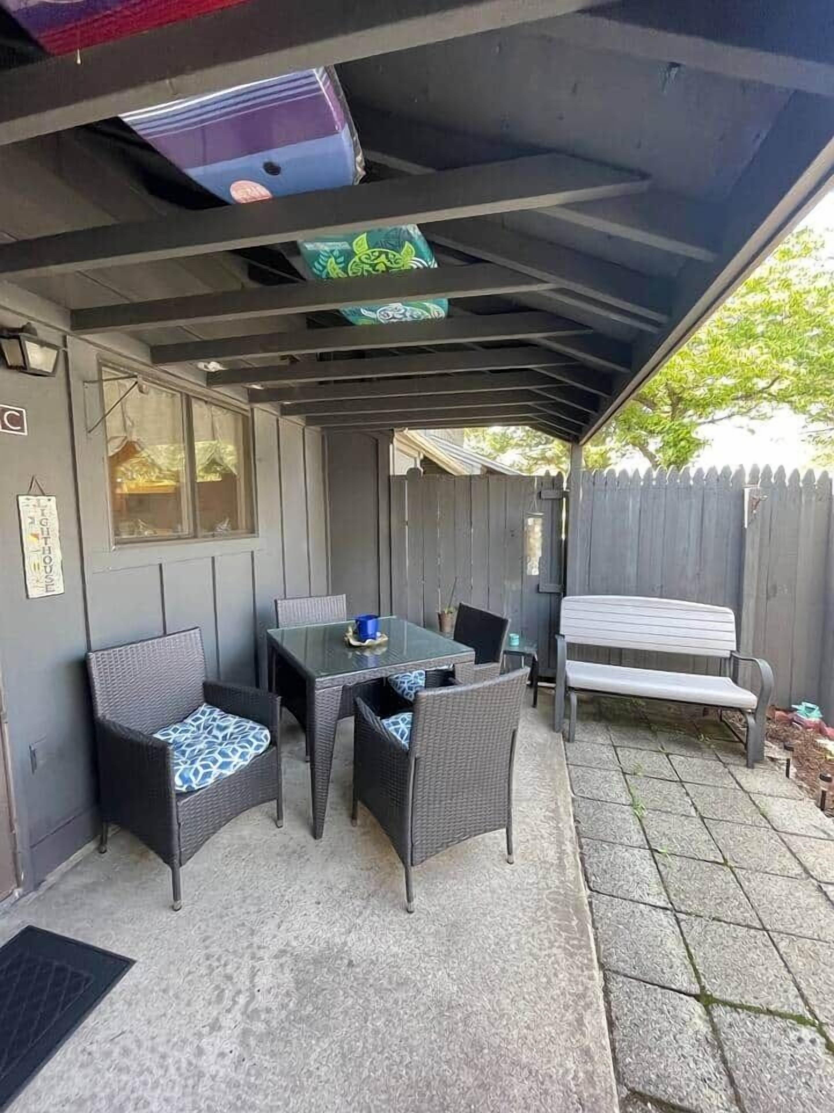 Een buitenpatio met een overdekte zithoek, een tafel en stoelen.