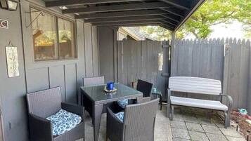 Une terrasse extérieure dotée d’un espace salon abrité, d’une table et de chaises.