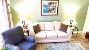 A living room with a sofa, armchair, and a framed picture on the wall. - Pink Flamingo-Pet-Friendly + Walk to Beach & Dining, Fenced courtyard (North Myrtle Beach)