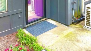 A house with a dark gray exterior, a purple door, and a welcome sign. - Pink Flamingo-Pet-Friendly + Walk to Beach & Dining, Fenced courtyard (North Myrtle Beach)