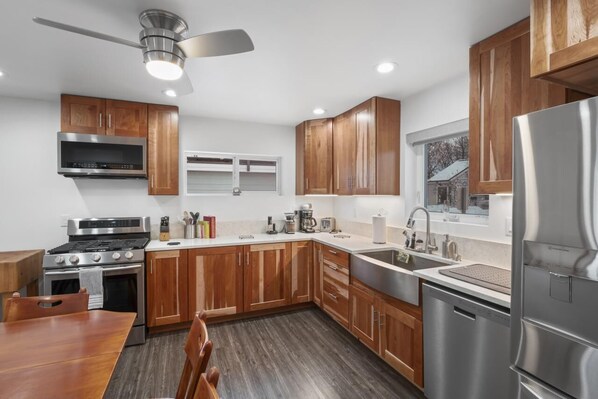 A modern kitchen with wooden cabinets, stainless steel appliances, and a dining area with a wooden table and chairs.