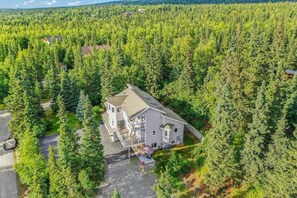 Ein zweistöckiges Haus, umgeben von dichtem Wald, mit einer Auffahrt zum Eingang.