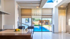 Una cucina moderna con zona pranzo, un'ampia finestra e vista su piscina e area barbecue.