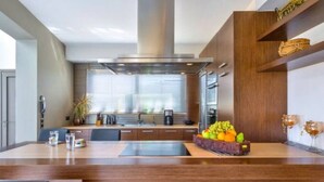 Una cucina moderna con isola centrale, mobili in legno e un espositore di frutta.