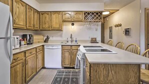 Une cuisine avec des meubles de rangement en bois, un plan de travail blanc, un lave-vaisselle et un évier.