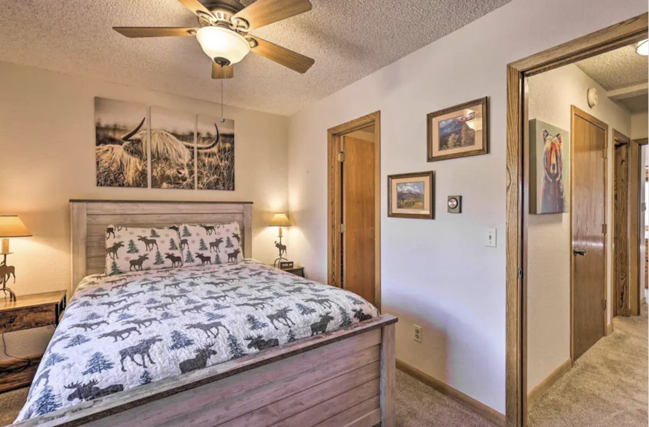 Une chambre à coucher avec un lit, un ventilateur de plafond et un mur décoré de tableaux encadrés.