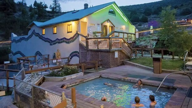 Une maison avec une piscine, entourée d’une terrasse et d’une clôture.
