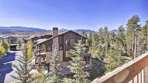 Un chalet moderne avec une façade en pierre, de nombreux balcons et une vue sur les montagnes environnantes.
