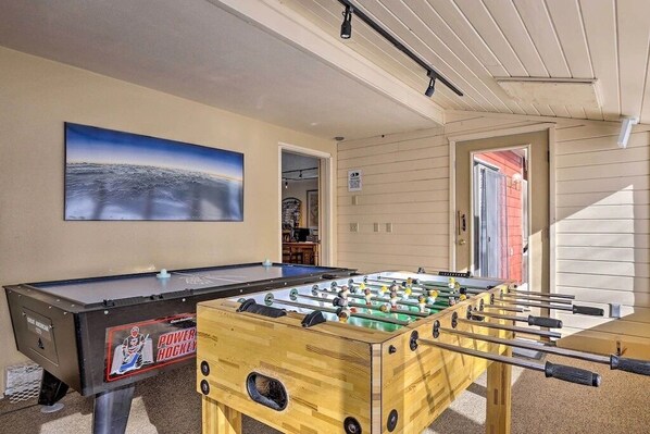A foosball table in a room with a large painting on the wall, wooden walls, and a door leading to another room. - Fraser 2Bed +Loft + 3 Bath, Mountain Views, Free WP Bus, Dog Friendly, Game Room (Fraser)