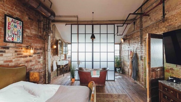A large room with a bed, a bathtub, and a TV.