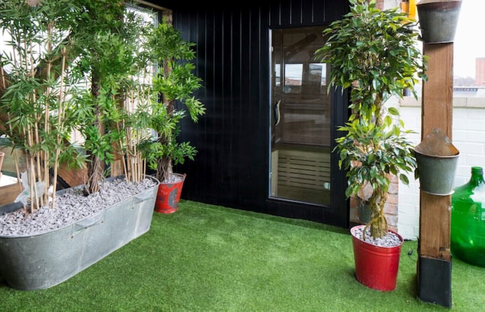 A garden with various potted plants and a small lawn area.