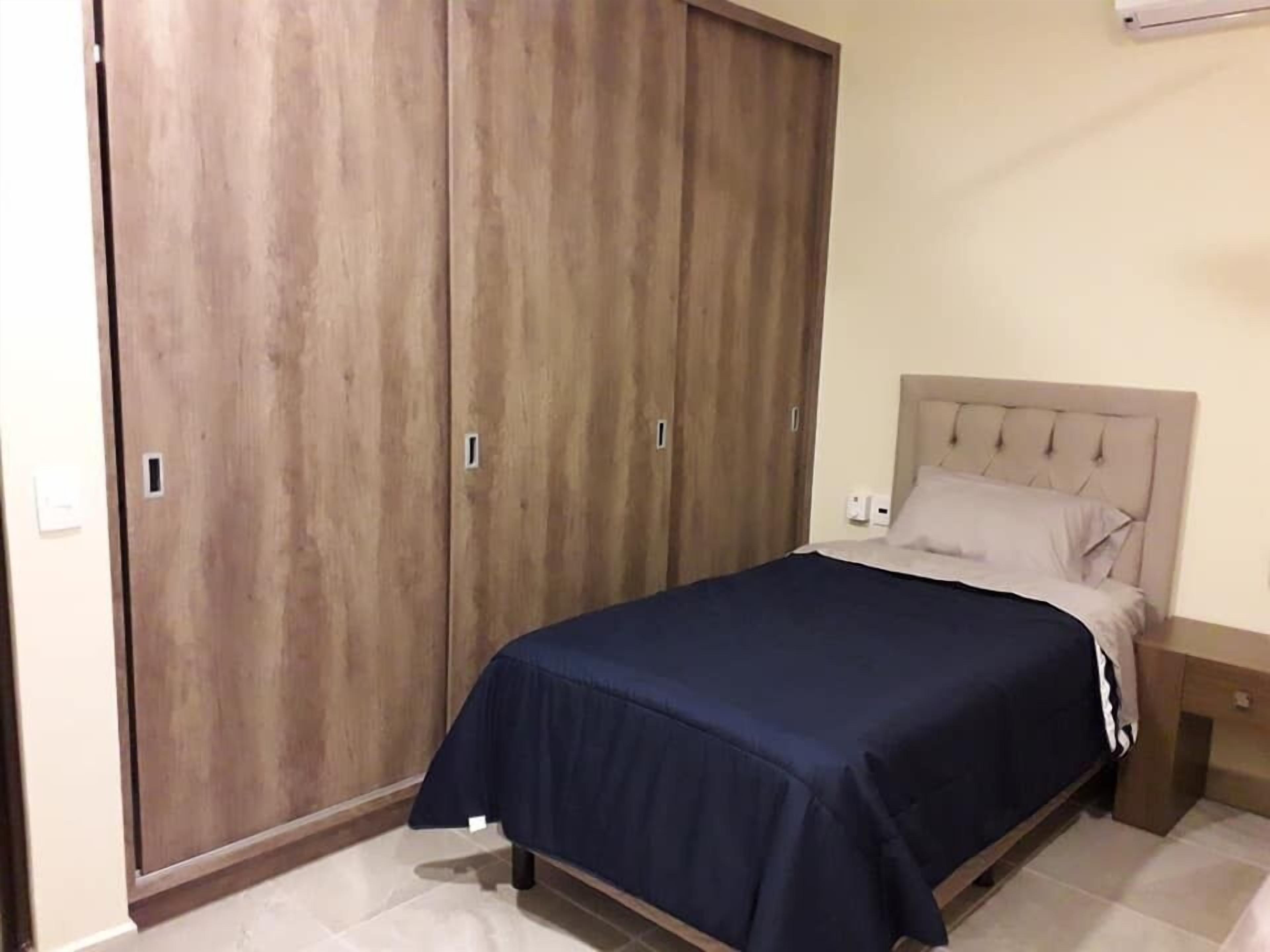 Quarto com uma cama, uma mesa de cabeceira e um guarda-roupa.