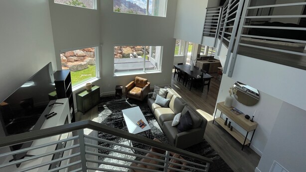 Un salón espacioso con un gran ventanal con vistas a un paisaje rocoso, una escalera y una zona de cocina.