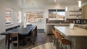 Una cocina moderna con zona de comedor, ventanas amplias y vistas a un paisaje rocoso.