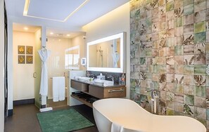 A modern bathroom with a bathtub, a large mirror, and a vanity with a sink and towel rack.