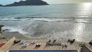 A deck with sun loungers overlooking a beach and ocean. - Depas Tramonto (Mazatlán)