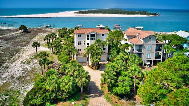 Une propriété située sur la côte, comprenant une grande maison, un bâtiment plus petit attenant et une vue sur la plage.