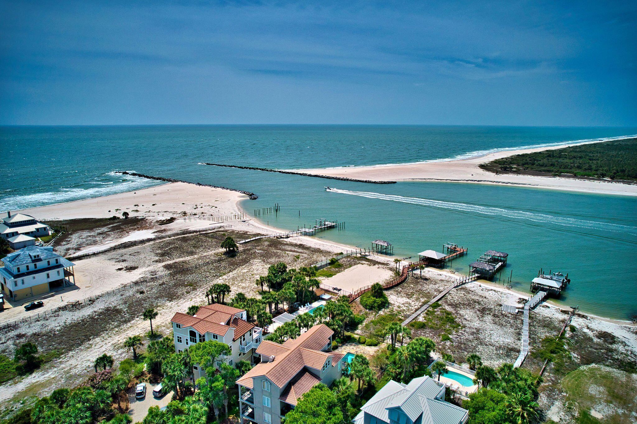 Vista aérea de uma área costeira com praia, píer e vários edifícios.