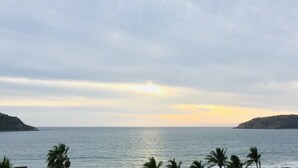 A coastal view with calm sea, distant hills, and palm trees. - Condos TT (Mazatlán)