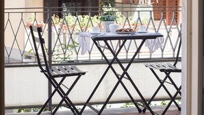 A balcony with a table set for two, a chair, and a potted plant. - GREGORY BIG FAMILY (Rome)