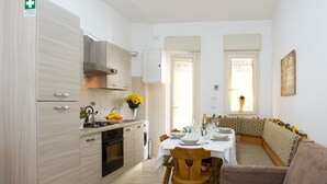 A compact kitchen with modern appliances, a dining area with a sofa and table set for a meal, and a view of the outdoors through a window. - GREGORY BIG FAMILY (Rome)