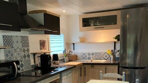 Eine Küche mit Esstisch, Stühlen, Kühlschrank und Mikrowelle.