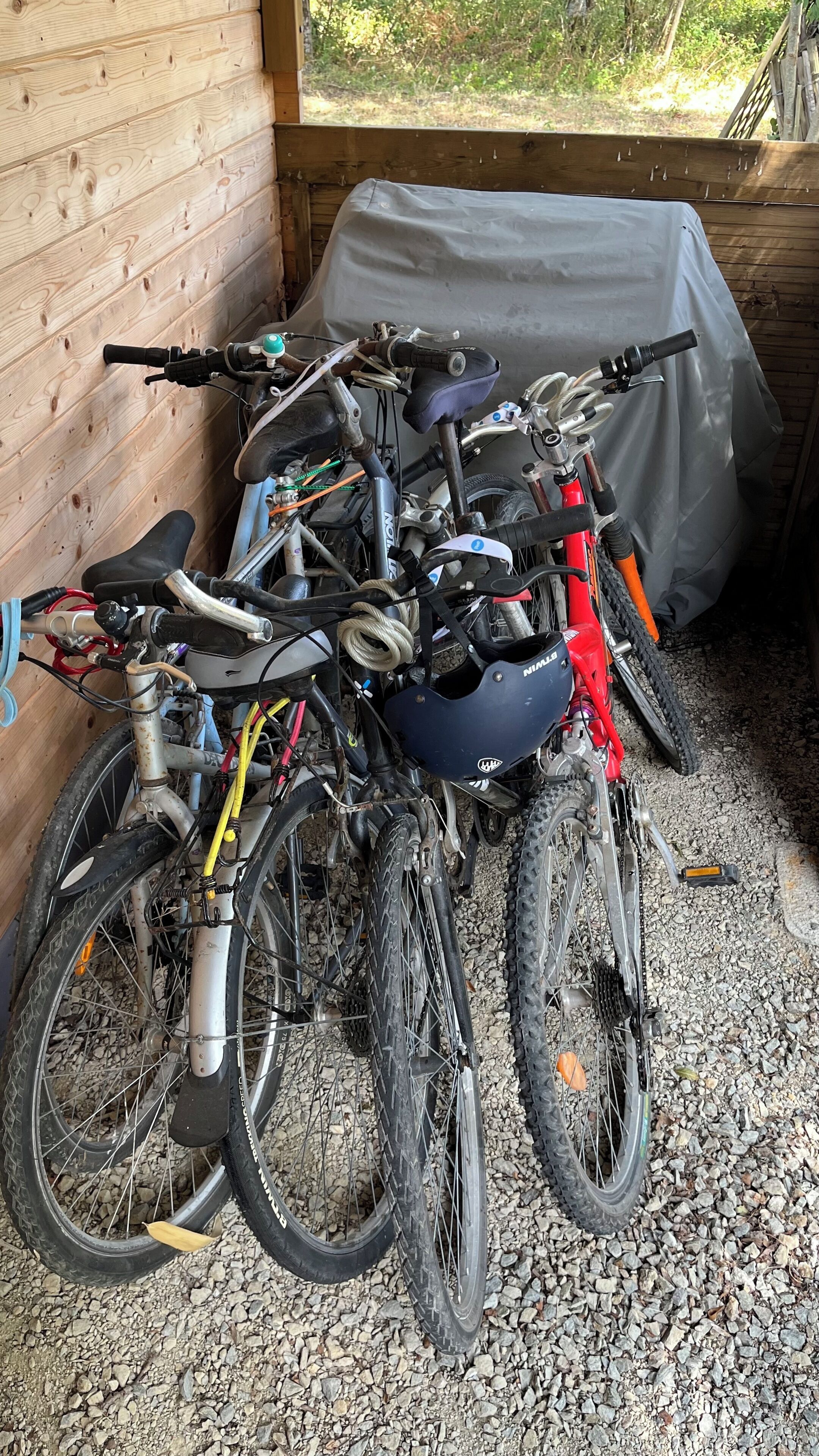 A covered outdoor area with bicycles parked against a wooden wall.