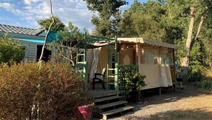 Ein rustikales Blockhaus mit Veranda, umgeben von Bäumen und blauem Himmel.