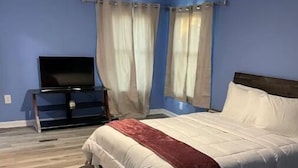 Un dormitorio con una cama, un televisor sobre un mueble bajo y un ventilador de techo.