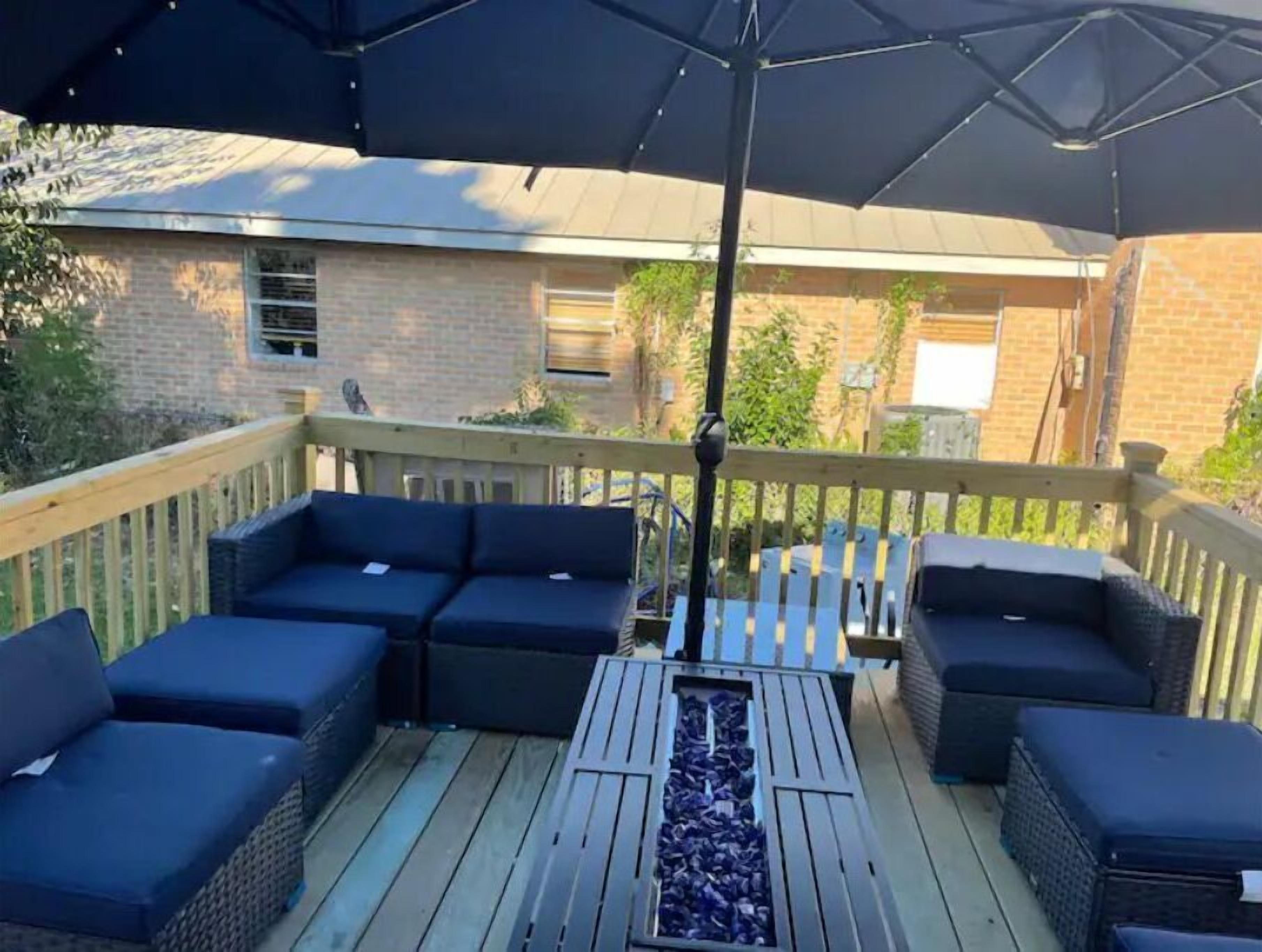 A covered outdoor deck with dark wicker furniture and a central fire feature.